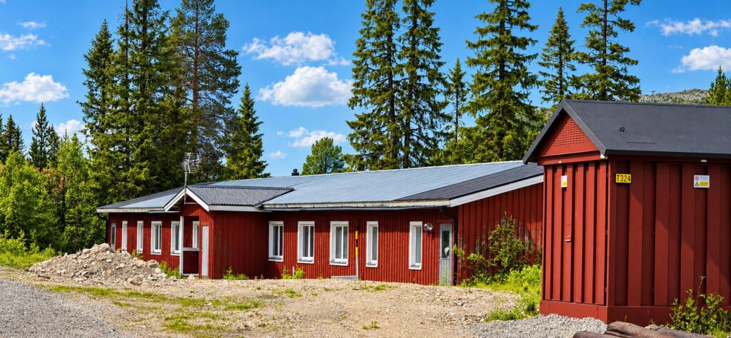 Vargen Base Camp, det röda huset bland granarna en sommardag